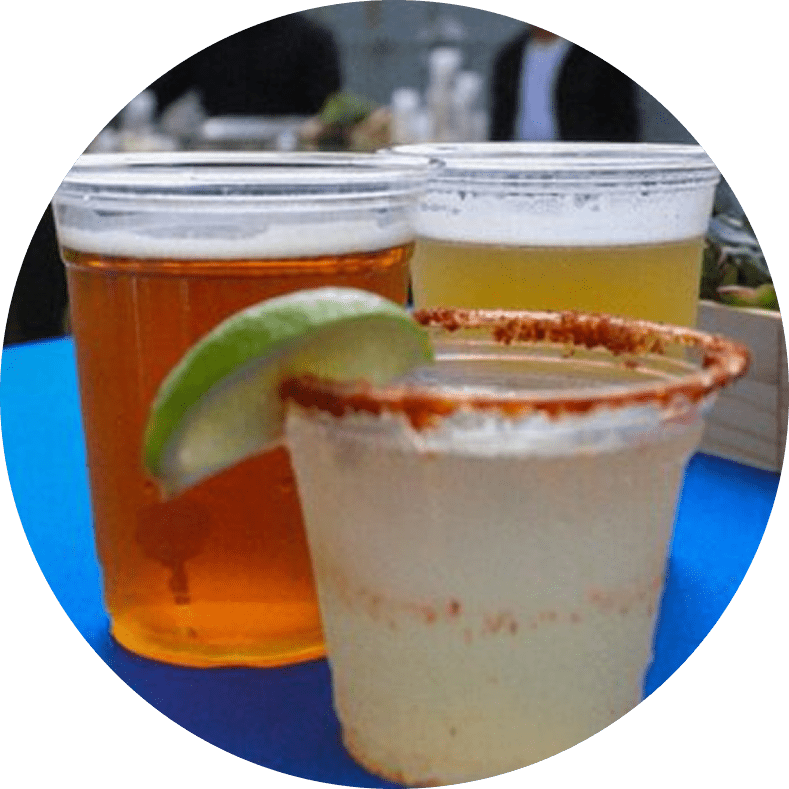 Three drinks in plastic cups with lime.