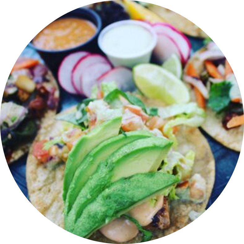 Tacos with avocado and lime on plate.